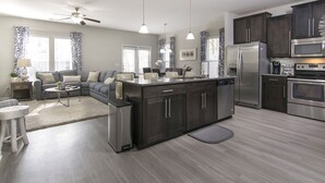 A modern kitchen with dark cabinetry, stainless steel appliances, and a central island. - ~BEAUTIFUL HOME NESTLED IN THE PERFECT TOWN~ (Bluffton)