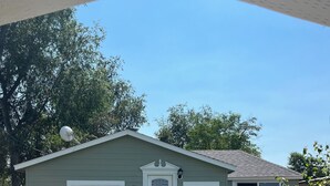 A single-story house with a white door, two windows, and a satellite dish on the roof.