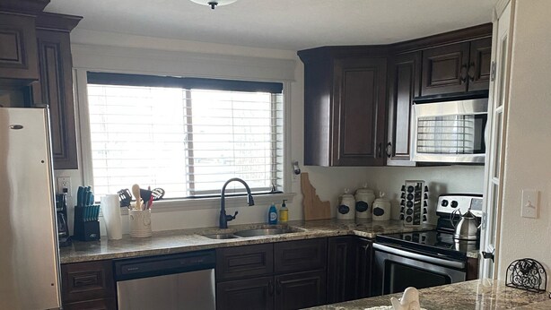 A kitchen with granite countertops, a built-in oven, a microwave, and a dishwasher.