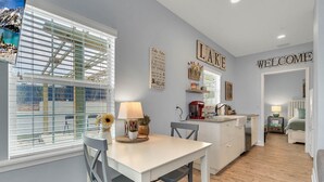 A modern kitchen with a white countertop, a dining table with chairs, and a view of a mountain through large windows.