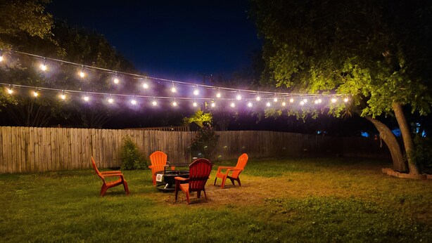 An outdoor patio area with a wooden fence, string lights, and outdoor furniture. - Central, Airport & Downtown: Hotel House Retreat (San Antonio)