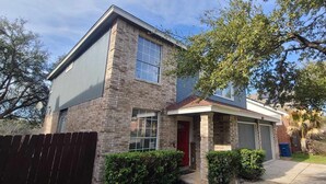 A two-story house with a brick exterior, a red door, and a garage. - Central, Airport & Downtown: Hotel House Retreat (San Antonio)