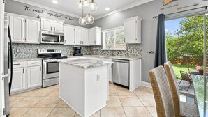 A modern kitchen with white cabinetry, a central island, a built-in oven, and a microwave. - Central, Airport & Downtown: Hotel House Retreat (San Antonio)