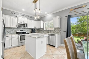 A modern kitchen with white cabinetry, a central island, a built-in oven, and a microwave. - Central, Airport & Downtown: Hotel House Retreat (San Antonio)