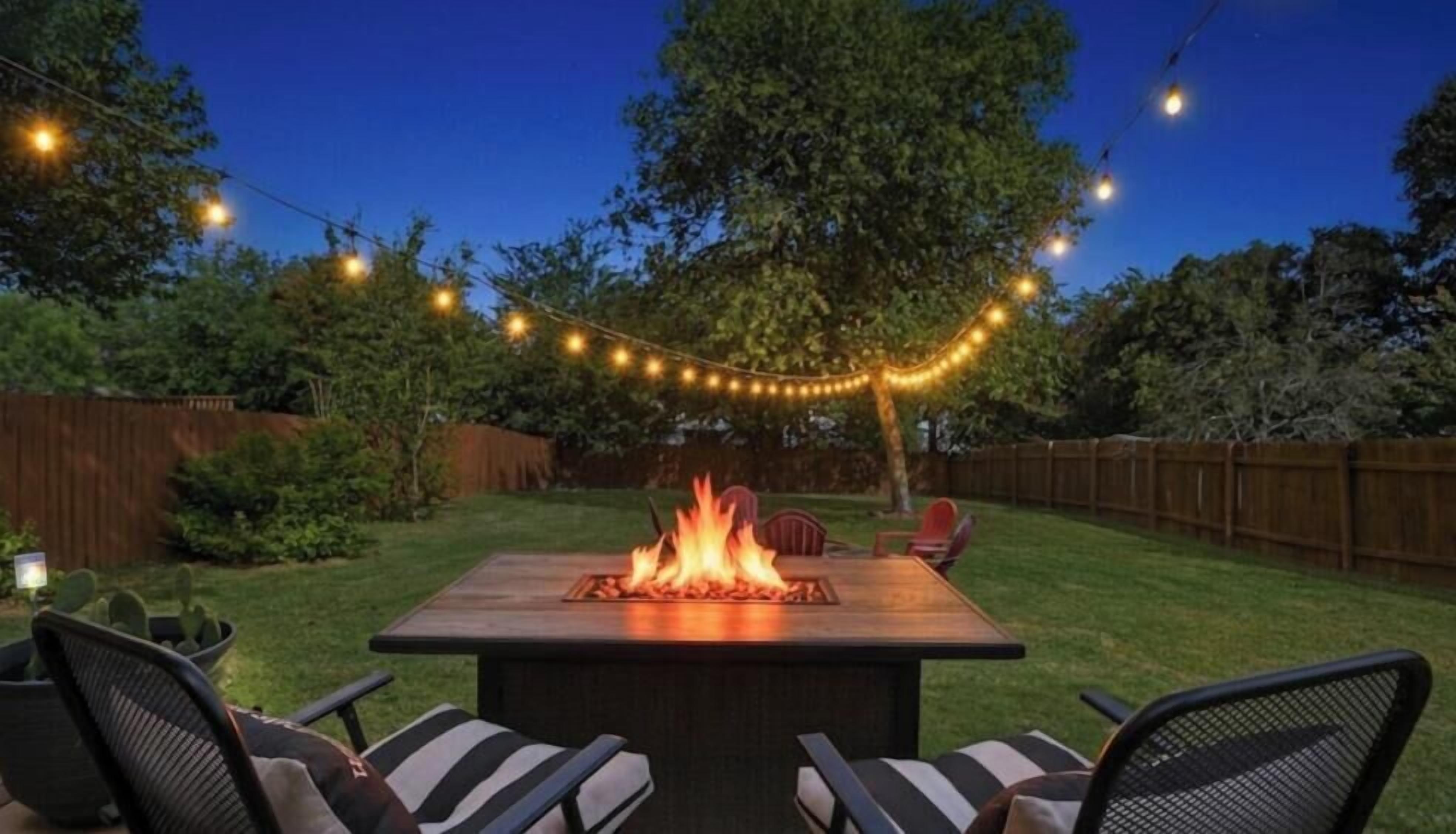 An outdoor patio with a fire feature, string lights, and seating.