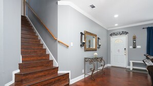 A staircase with wooden steps and a handrail, a white door with a decorative mirror above it, and a bench in the foreground. - Central, Airport & Downtown: Hotel House Retreat (San Antonio)