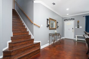 A staircase with wooden steps and a handrail, a white door with a decorative mirror above it, and a bench in the foreground. - Central, Airport & Downtown: Hotel House Retreat (San Antonio)