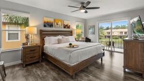 A bedroom with a wooden bed, nightstands, a ceiling fan, and artwork on the walls.