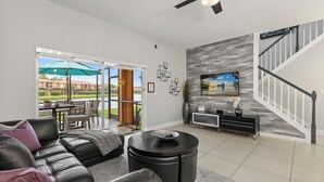 A modern living room with a black leather sofa, a round coffee table, and a dining area with outdoor seating. - Park all day, recharge in style- 10min to Disney, clean, revamped w/ resort pool (Kissimmee)