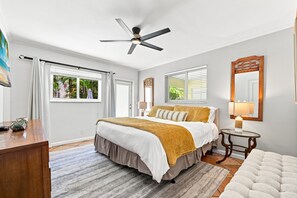 A bedroom with a bed, a ceiling fan, a window with blinds, a bedside table, and a nightstand.