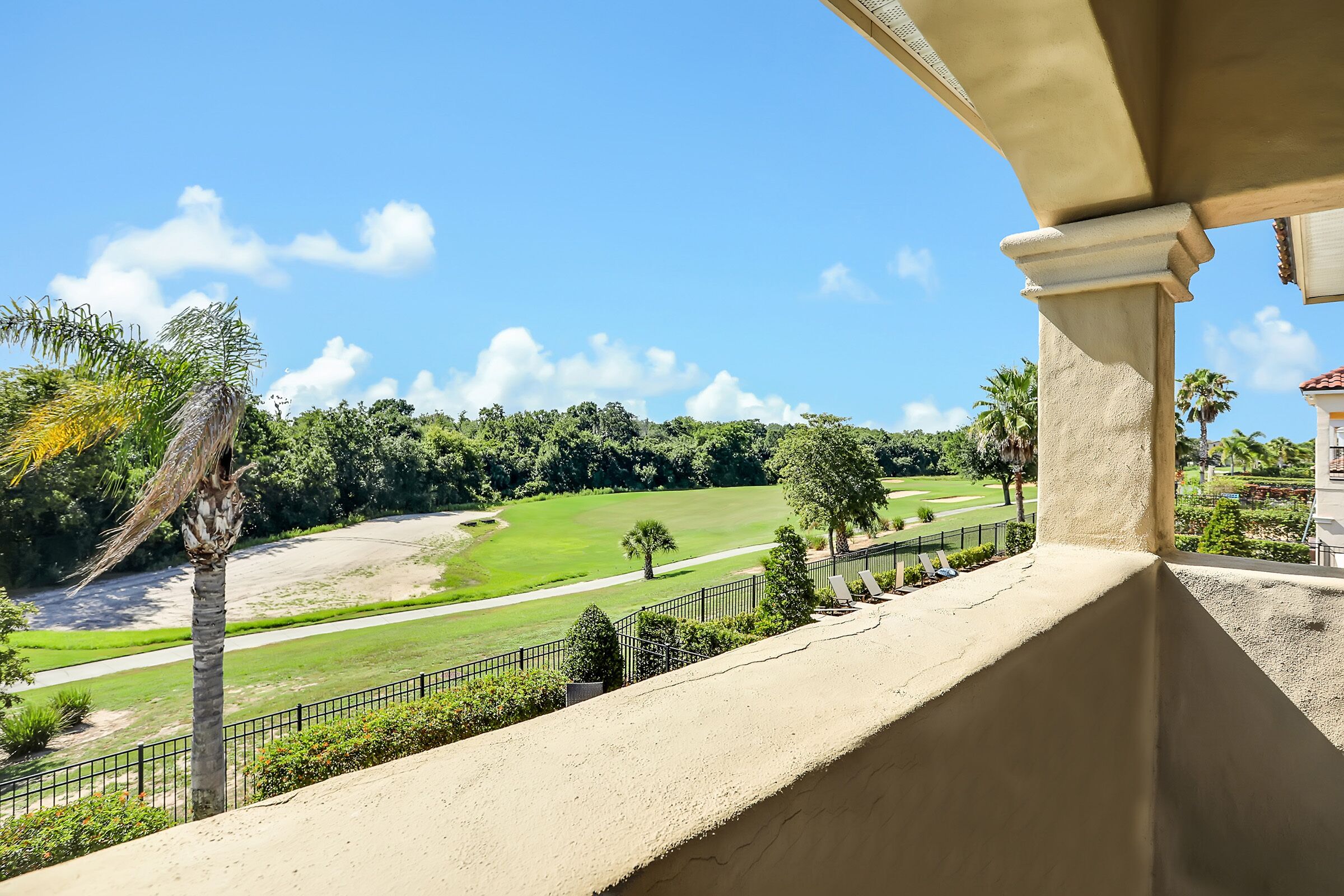 A view from a balcony overlooking a golf course with a clear sky.