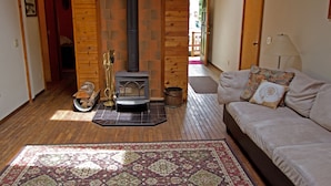 A cozy living room with a fireplace, a sofa, and a patterned rug.