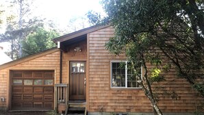 A wooden house with a garage, a front door, and a window.
