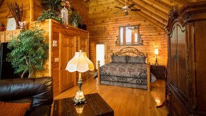 A log cabin bedroom with a bed, a dresser, a mirror, and a ceiling fan. - ✧Queen Cabin - wait until you see the BATHROOM! (Dryfork)