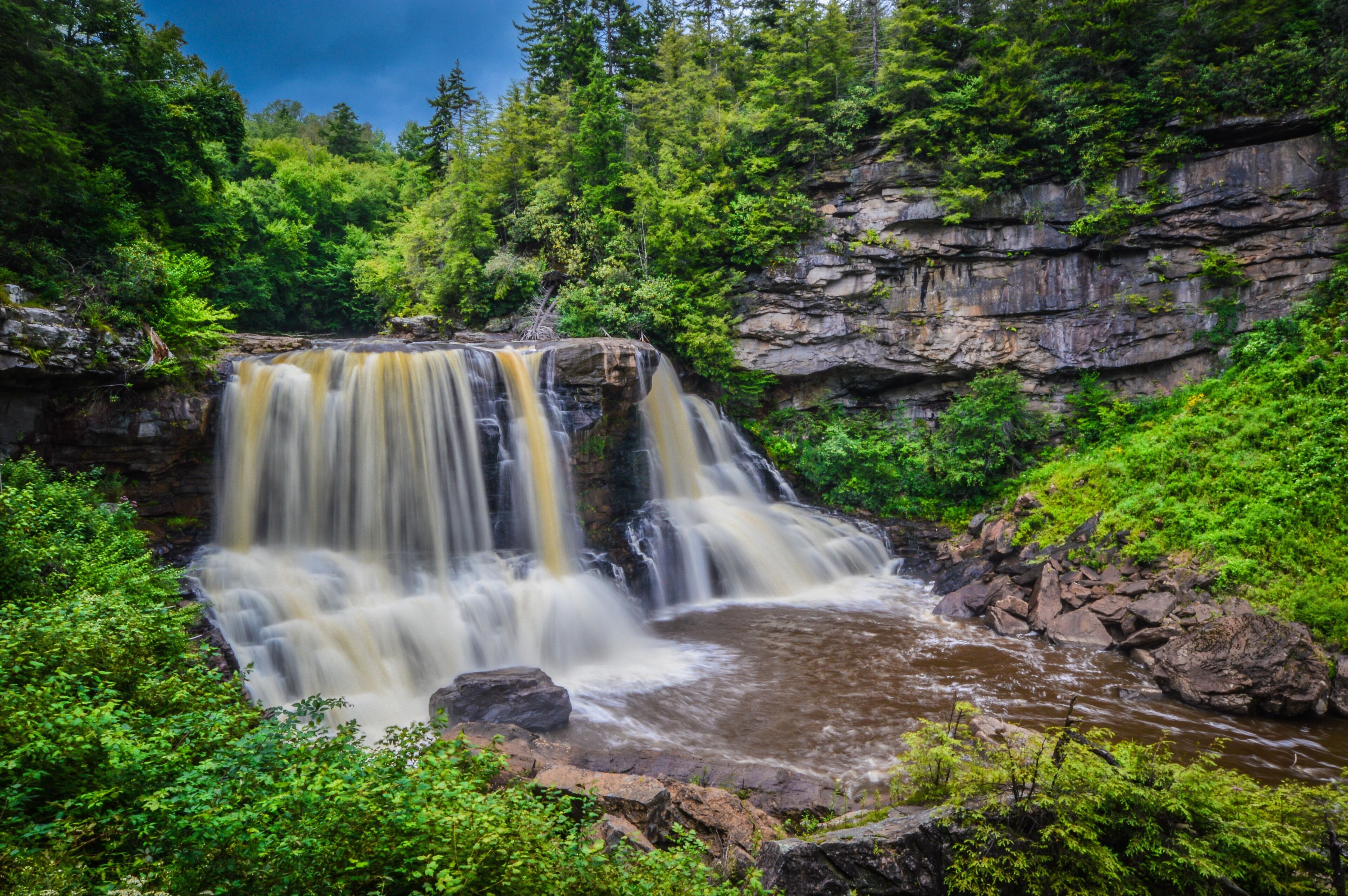 A waterfall surrounded by lush greenery and rocky cliffs.