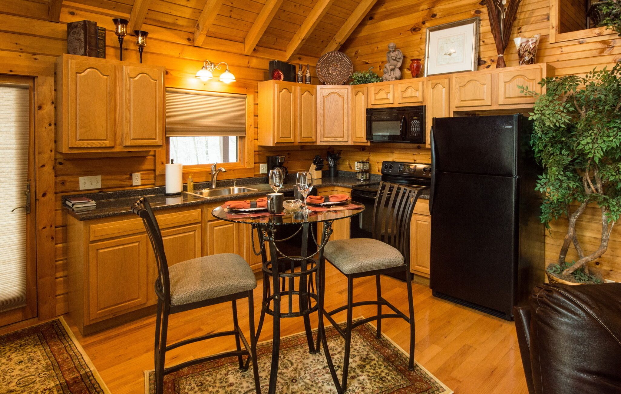 A wooden cabin-style kitchen with a dining table, chairs, and a refrigerator.