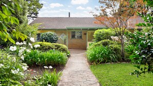 A garden pathway leading to a building with a tiled roof and a brick facade. - Dogs Stay Free. Cosy Restful Retreat with Fireplace. (Wentworth Falls)