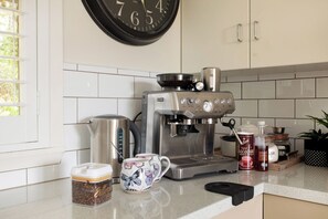 Una cocina con cafetera, un reloj y varios utensilios.