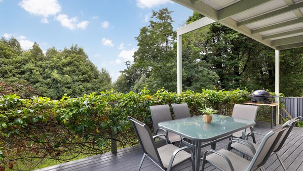 An outdoor patio with a glass table and chairs, surrounded by a wooden deck and a covered area. - Dogs Stay Free. Cosy Restful Retreat with Fireplace. (Wentworth Falls)
