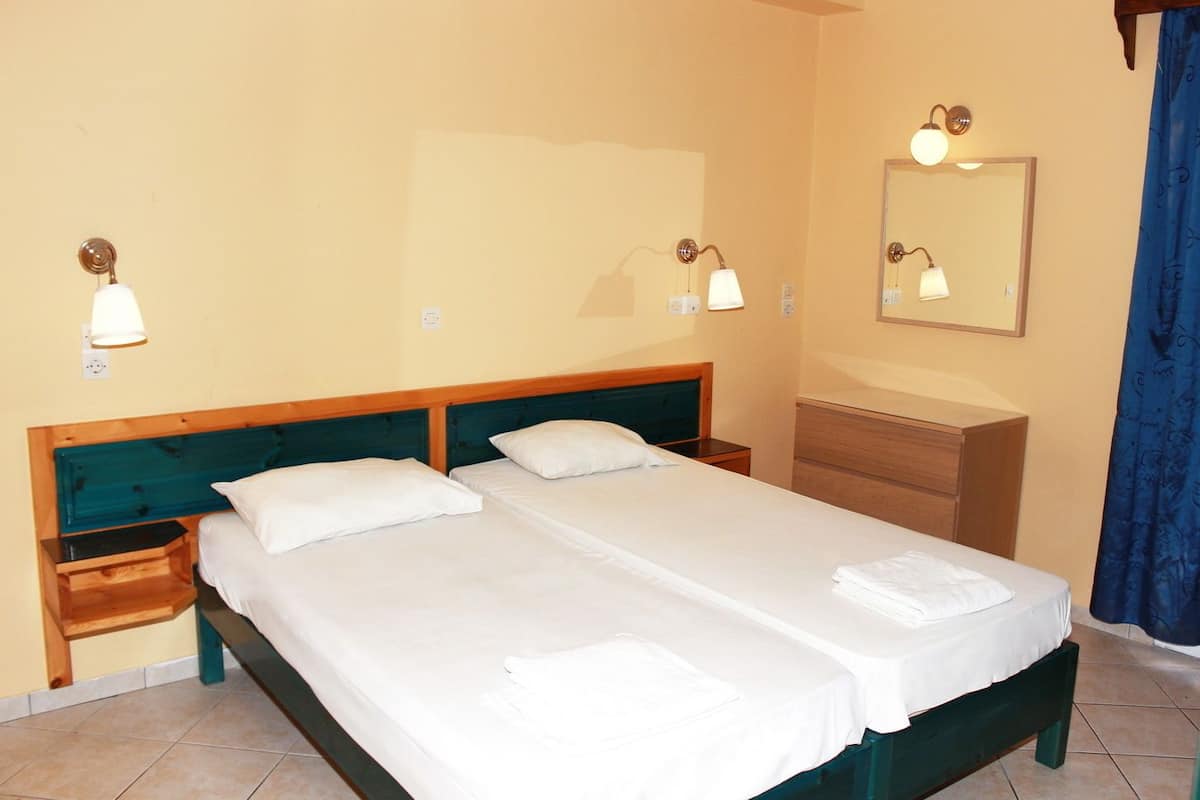 A double bed with a wooden headboard, two bedside tables, a nightstand, a dresser, and a mirror on the wall.