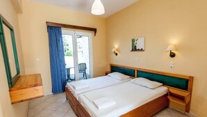 Habitación de hotel con dos camas, cabecera de madera, una mesita pequeña y una silla cerca de la puerta.