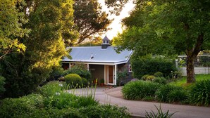 A quaint house with a sloped roof, surrounded by lush greenery and a well-maintained garden. - Haiku- charming oasis in Daylesford (Daylesford)