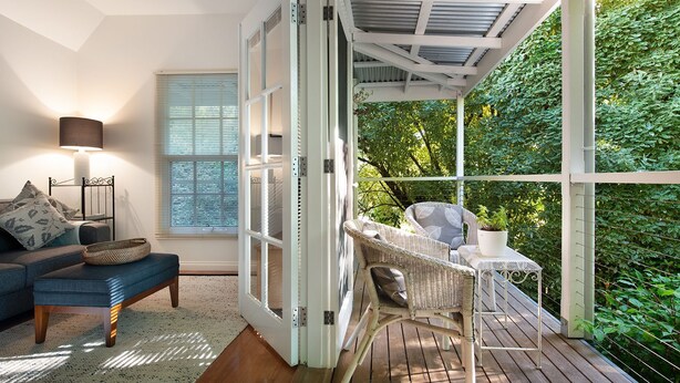 A cozy room with a sofa, a table, and a chair, a window with blinds, and a view of greenery outside. - Haiku- charming oasis in Daylesford (Daylesford)