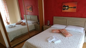 A hotel room with two beds, a wooden headboard, a nightstand with a lamp, and a mirror reflecting the room. - "Modern cozy renovated apartment is waiting for you in the heart of Athens.  (Athina)