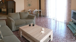 A living room with a sofa, a coffee table, and a TV. There is a dining area with a table and chairs. The room has a kitchen in the background. - "Modern cozy renovated apartment is waiting for you in the heart of Athens.  (Athina)