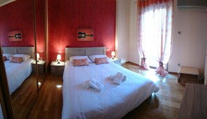 A hotel room with two beds, red walls, and a large mirror. - "Modern cozy renovated apartment is waiting for you in the heart of Athens.  (Athina)