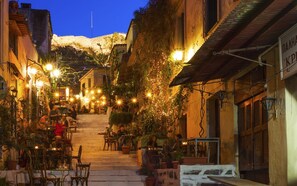 A narrow street with outdoor seating, potted plants, and string lights. - "Modern cozy renovated apartment is waiting for you in the heart of Athens.  (Athina)