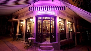 A restaurant with a neon sign, outdoor seating, and a covered entrance. - "Modern cozy renovated apartment is waiting for you in the heart of Athens.  (Athina)