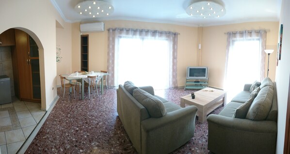 A living room with a sofa set, a coffee table, a TV, and a dining area with chairs and a table. - "Modern cozy renovated apartment is waiting for you in the heart of Athens.  (Athina)