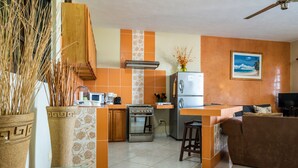 Une cuisine dotée d’un îlot central, d’un réfrigérateur, d’un four et d’un coin repas avec un canapé.