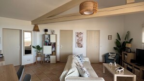 Un'ampia zona giorno con divano, tavolo da pranzo, sedie, televisore e lampadario.