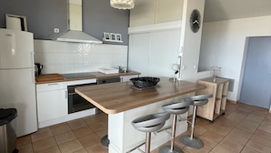 Una cucina moderna con mobili bianchi, un piano di lavoro in legno, forno integrato, lavello e lampadario.