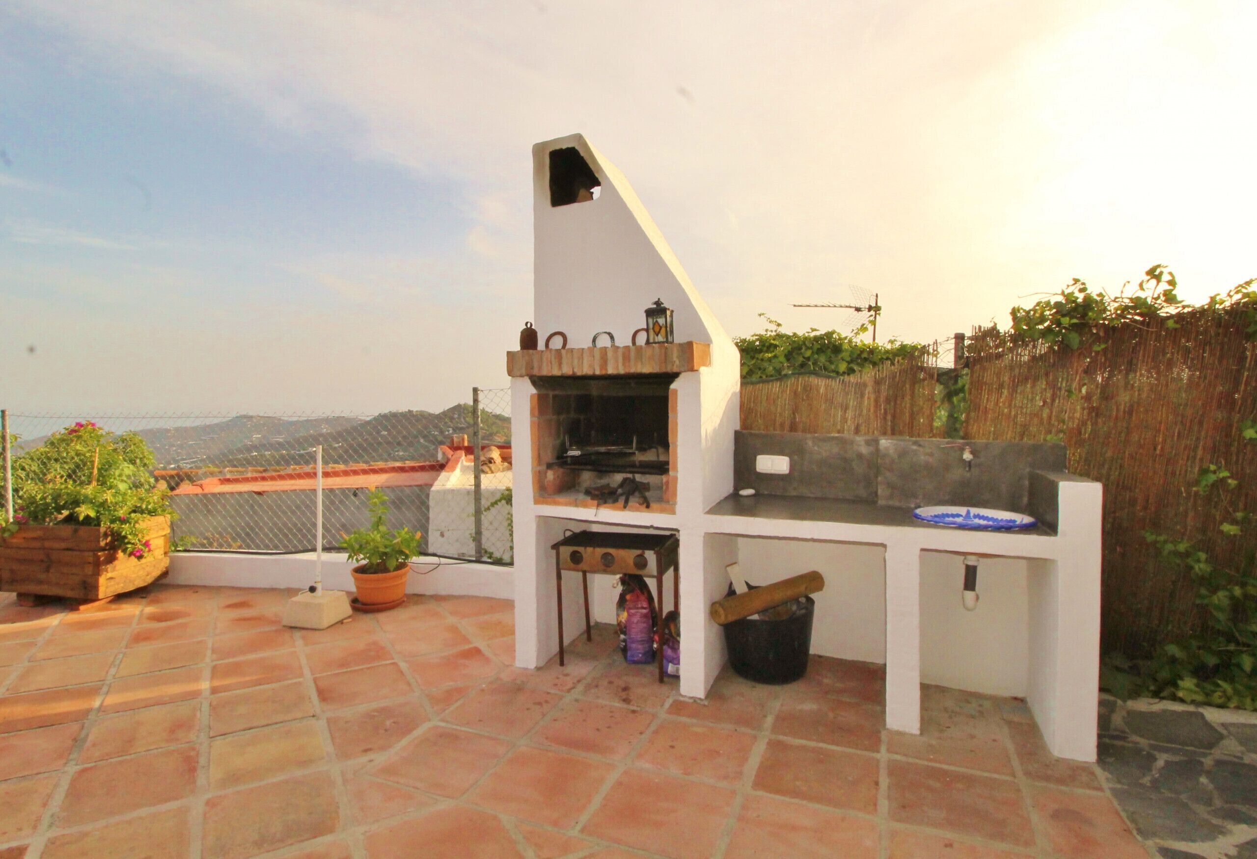 An outdoor patio with a barbecue grill, a small table, and potted plants.
