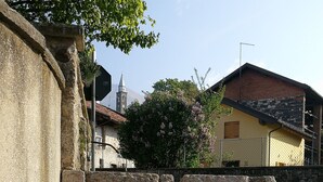 Un mur de pierre surmonté d’un jardon en forme de tonneau en bois, rempli de fleurs.
