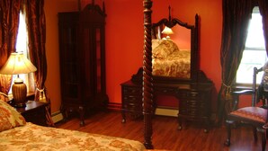 Une chambre à coucher avec un lit à baldaquin, une commode en bois, une chaise et une table de chevet avec une lampe.