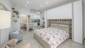 Un dormitorio moderno con una cama grande, un sofá gris y un armario empotrado.