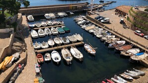 A marina with numerous boats docked, a stone wall, and a clear view of the sea. - Beautiful Apartment with Sea Views and the Port of Fornells (Fornells)