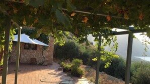 An outdoor patio with a table and chairs, surrounded by greenery and a view of the sea. - Bed & Breakfast Baglio Fanara # 2 (Suite) (San Vito lo Capo)