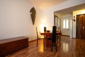A dining area with a wooden table and chairs, a bench, and a wall-mounted decorative piece. - Rialto Apartment Vatican Museums (Rome)