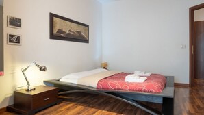 A modern bedroom with a bed, bedside table, lamp, and artwork on the wall.