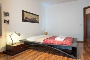 A modern bedroom with a bed, bedside table, lamp, and artwork on the wall. - Rialto Apartment Vatican Museums (Rome)