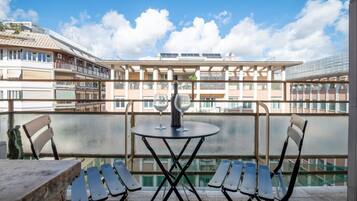 Un balcon avec une table et des chaises, une bouteille de vin et une vue sur un immeuble doté de balcons et de fenêtres.