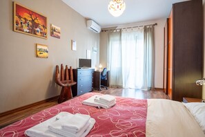 A hotel room with a bed, a desk, a chair, a TV, and artwork on the walls. - Rialto Apartment Vatican Museums (Rome)