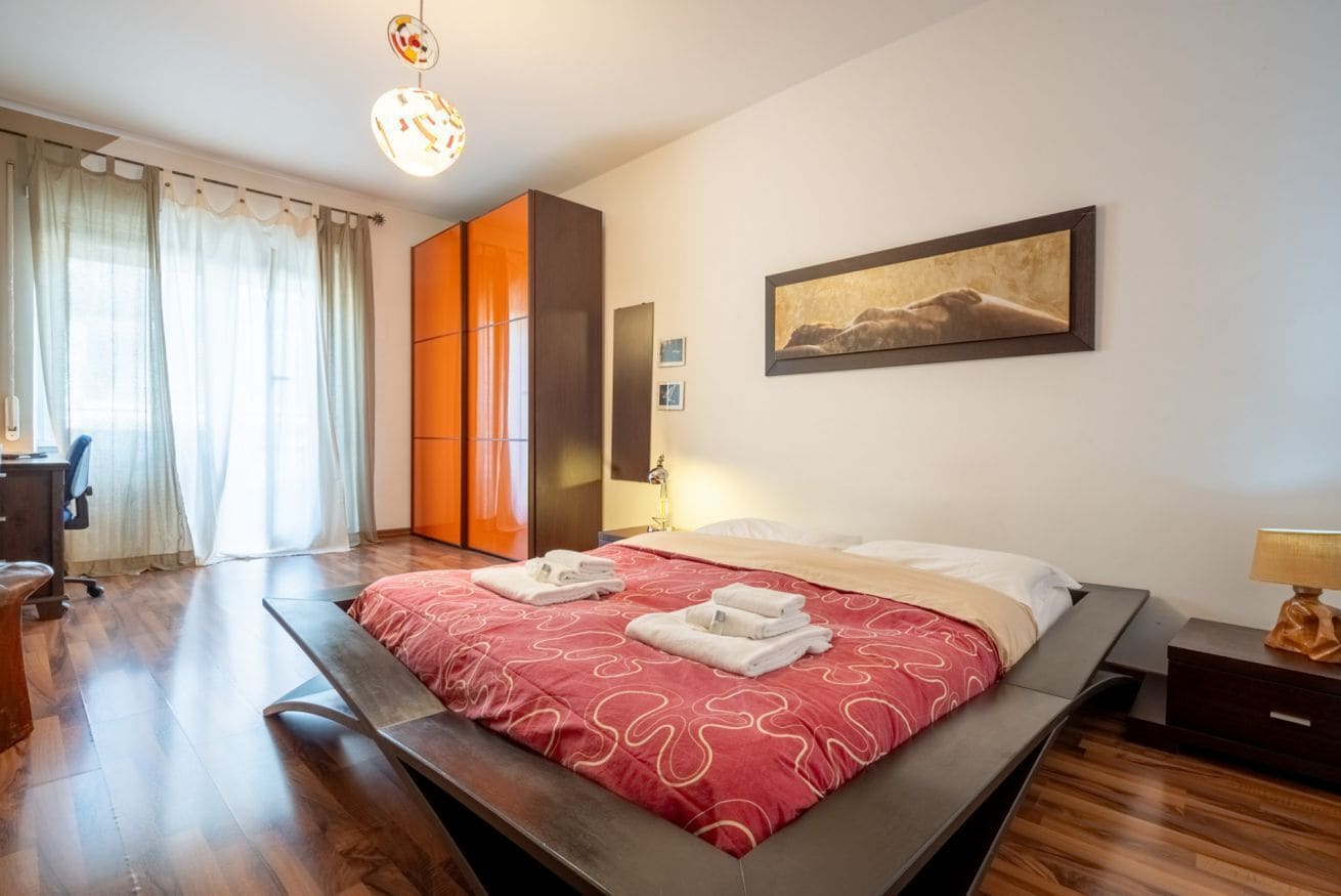 Une chambre à coucher avec un lit, un bureau, une chaise, une armoire et un tableau accroché au mur.