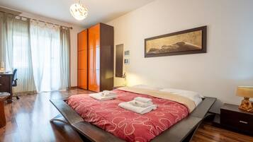 Une chambre à coucher avec un lit, un bureau, une chaise, une armoire et un tableau accroché au mur.