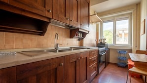 A kitchen with wooden cabinets, a stainless steel sink, and a window overlooking a balcony.